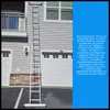 A tall aluminum ladder is leaning against a house with two garage doors. Podgląd zdjęcia produktu