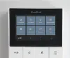 A close-up view of a DoorBird IP video indoor station with a touchscreen interface displaying various icons and options. Produktbild-Vorschau