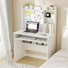 A white desk with a laptop, keyboard, and books, set up in a bedroom next to a bed. Anteprima dell’immagine prodotto