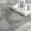 A close-up view of a fluffy gray rug with a white tray containing decorative items placed on it. Anteprima dell’immagine prodotto