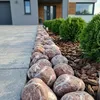 Große rot-weiß gemaserte Kieselsteine als Beeteinfassung neben Rindenmulch an einer Einfahrt Produktbild-Vorschau