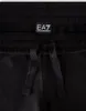 A close-up view of the waistband and drawstring of black sweatpants, featuring a prominent EA7 logo tag. Produktbild-Vorschau
