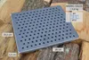 A cast iron grate with dimensions and model information displayed, resting on a pile of firewood. Voir les images du produit