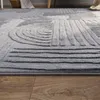 A close-up view of a textured gray rug with a geometric pattern, placed on a wooden floor. Anteprima dell’immagine prodotto