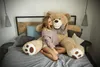 A woman is sitting on a bed with a large teddy bear. Podgląd zdjęcia produktu
