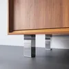 A close-up view of the bottom of a wooden cabinet with chrome legs. Produktbild-Vorschau