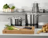 A set of stainless steel pots and pans on a stovetop, with fresh vegetables and potatoes nearby. Produktbild-Vorschau