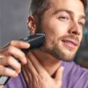 A man is trimming his beard with an electric trimmer. Produktbild-Vorschau