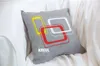A gray pillow with a geometric design is placed on a white couch. Anteprima dell’immagine prodotto