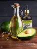 Avocado oil in bottles with fresh avocados on a wooden surface. Anteprima dell’immagine prodotto