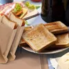 A close-up of toasted bread slices in reusable toaster bags, with a breakfast spread in the background. Produktbild-Vorschau
