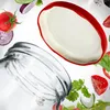 A collection of canning jar lids and fresh ingredients are arranged in a dynamic composition against a white background. Podgląd zdjęcia produktu