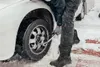 A person changing a car tire in the snow. Voir les images du produit