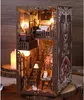 A miniature, illuminated book nook designed to look like a multi-story building interior, with stairs, furniture, and decorative elements. Voir les images du produit