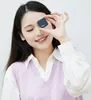 A young woman is holding a small black device in front of her eye. Podgląd zdjęcia produktu