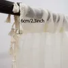 Close-up of a curtain rod with a cream-colored sheer curtain hanging from it. Tassels are visible along the edge of the curtain. Produktbild-Vorschau