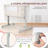 A beige baby bassinet with a gray adjustable stand, shown in a room with a wooden floor and a white rug. The image highlights the height adjustability feature with text and diagrams. Produktbild-Vorschau