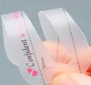 A close-up shot of a person's hand holding a clear plastic eyebrow stencil. Podgląd zdjęcia produktu