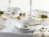 A beautifully set dining table with white porcelain plates, gold cutlery, and decorative elements. Náhľad obrázku produktu