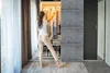 A woman is standing in front of an open closet, looking at her clothes. Produktbild-Vorschau