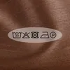 A close-up of a fabric with laundry care symbols. Náhled obrázku produktu