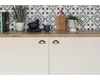 A kitchen countertop with a backsplash, cabinet doors, and various decorative items. Produktbild-Vorschau