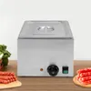 A stainless steel electric sausage warmer with a knob and a switch on the front, placed on a wooden surface. There are sausages on a cutting board to the left and right of the warmer. Náhled obrázku produktu