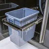 A close-up view of a pull-out trash bin system with a gray plastic bin inside a stainless steel frame, integrated into a larger unit. Náhľad obrázku produktu