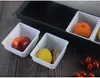 A close-up view of a black bar container with multiple white inserts holding fruits and other food items, set against a wooden background. Produktbild-Vorschau