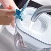 A person is filling a Brita water filter pitcher with water from a faucet. Náhled obrázku produktu