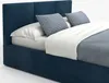 A close-up view of a dark blue upholstered bed with white and light blue bedding and pillows. Náhľad obrázku produktu