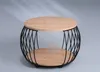 A round coffee table with a wooden top and bottom shelf, supported by a black metal frame. Produktbild-Vorschau