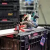 A circular saw and a clamp are positioned on a piece of wood, which is resting on a stack of black toolboxes. Podgląd zdjęcia produktu
