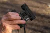 A hand holding a pair of black binoculars. Podgląd zdjęcia produktu