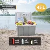 A portable cooler filled with drinks and fruit is placed on a sandy beach next to a lake. Produktbild-Vorschau
