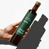 A hand holding a bottle of GreatVita Schwarzkümmelöl against a light background with a shadow. Produktbild-Vorschau