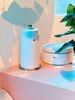 A white kitchen roll holder and a matching container are placed on a pink surface, with soft lighting casting shadows and reflections. Produktbild-Vorschau