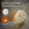 A person is holding a small, white, cat-shaped night light that is illuminated. Podgląd zdjęcia produktu
