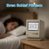 A person sleeping in bed next to a vintage computer-like alarm clock. Produktbild-Vorschau