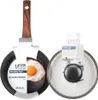 A frying pan and a pot lid are displayed side-by-side against a white background. The frying pan has a fried egg in it, and the pot lid is in its packaging. Náhľad obrázku produktu