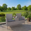 A poly-rattan bench with a table in the middle, placed on a balcony with a view of a green park and trees. Anteprima dell’immagine prodotto