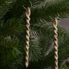 Two gold glitter icicle ornaments hang from a Christmas tree branch. Anteprima dell’immagine prodotto