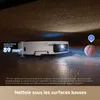 A robot vacuum cleaner is cleaning under a piece of furniture, demonstrating its low-profile cleaning capability. Produktbild-Vorschau