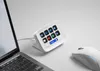 A white Elgato Stream Deck Neo with 8 illuminated buttons is placed on a white desk next to a laptop and a white computer mouse. Náhled obrázku produktu