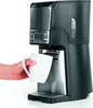 A coffee maker is brewing coffee into a mug held by a person's hand. Produktbild-Vorschau