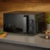A black Severin microwave oven is placed on a countertop in a kitchen setting. Produktbild-Vorschau