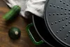 A close-up of a green cast iron pot with a textured lid and a green handle, next to two zucchinis on a wooden surface. Produktbild-Vorschau