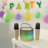 A karaoke speaker and two microphones are set up on a table, with colorful balloons and a 'PARTY' banner in the background, suggesting a festive atmosphere. Produktbild-Vorschau
