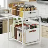 A white two-tier kitchen organizer shelf filled with various jars and bottles, placed on a kitchen countertop. Voir les images du produit