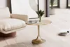 A modern living room scene with a gold side table next to a cream-colored armchair. Magazines are placed on the floor nearby. Voir les images du produit